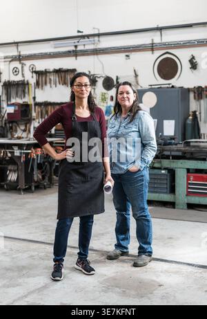 Mischlingsfrau mit Brille, die mit einer kaukasischen Kollegin am Arbeitsplatz steht Stockfoto