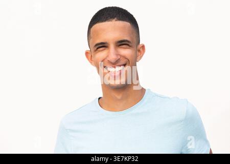 Lächelnder arabischer männlicher Teenager, der vor weißem Hintergrund steht Stockfoto
