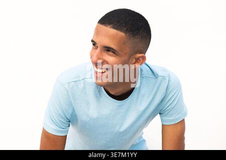 Lächelnder arabischer männlicher Teenager, der wegschaut und sich vor weißem Hintergrund stützt Stockfoto