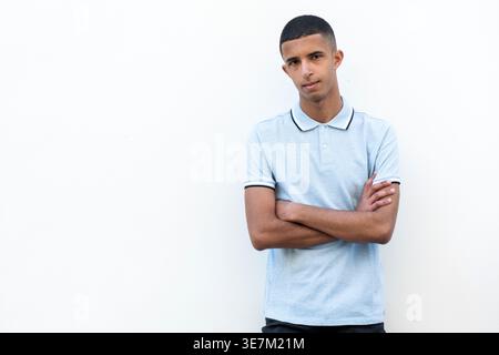 Ernster arabischer männlicher Teenager, der mit gekreuzten Armen vor weißem Hintergrund steht Stockfoto