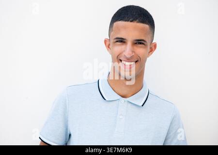 Lächelnder arabischer männlicher Teenager, der vor weißem Hintergrund steht Stockfoto
