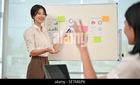 Lächelnde asiatische Geschäftsfrau steht und leitet das Team-Meeting im Büro Stockfoto