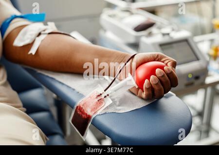 Schwarzer Frauenarm spendet Blut mit rotem Herz-Squeeze-Ball, der im Krankenhausbett in der Klinik liegt Stockfoto