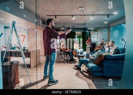 Ein bärtiger Mann aus dem Nahen Osten demonstriert, wie man Drohnen vor verschiedenen Teams am Arbeitsplatz benutzt Stockfoto