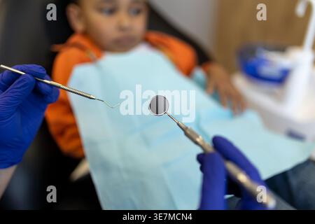 Schwarzer Junge bei Zahnbehandlung mit männlichem Zahnarzt in der Klinik Stockfoto