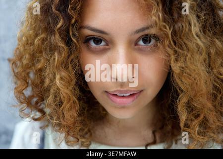 Ernste schwarze Frau, die vor grauem Hintergrund steht Stockfoto