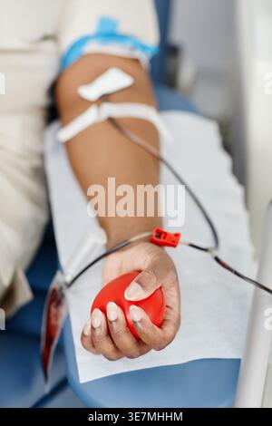 Schwarze Frau mit rotem Herz-Squeeze-Ball auf Krankenhausbett liegend Blutspende in der Klinik Stockfoto