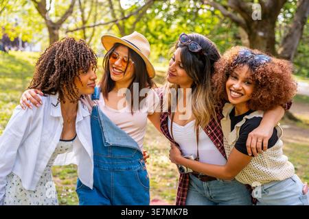 Lächelnde Gruppe weiblicher Freunde, die sich umarmen, während sie im Park stehen Stockfoto