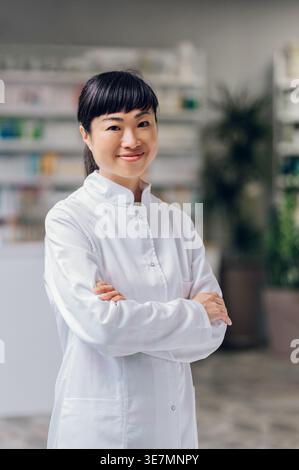 Japanische Apothekerinnen kreuzten sich die Arme, wenn sie in der Apotheke gegen den Zähler stehen Stockfoto