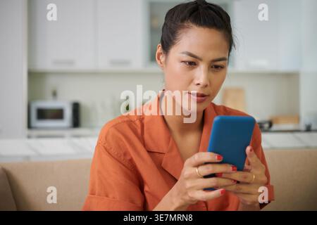 Frau mit gemischter Rasse, die zu Hause im Wohnzimmer auf dem Sofa sitzt Stockfoto