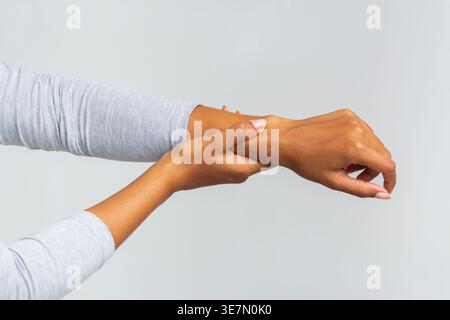 Zugeschnittene Bilder einer schwarzen Frau, die an Arthritis leidet, die ihr Handgelenk vor grauem Hintergrund im Studio reibt Stockfoto