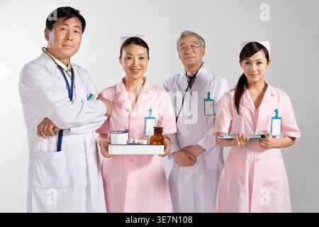 Chinesische Ärztinnen und Krankenschwestern mit Medizinstabletts, die im Krankenhaus an der grauen Wand stehen Stockfoto