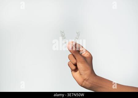 Hand eines kubanischen männlichen Teenagers mit klaren Zahnlindern vor weißem Hintergrund im Atelier Stockfoto