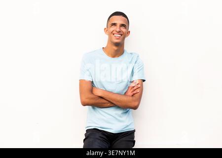 Lächelnder arabischer männlicher Teenager, der mit gekreuzten Armen auf weißem Hintergrund steht Stockfoto