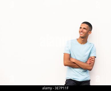 Lächelnder arabischer männlicher Teenager, der mit gekreuzten Armen auf weißem Hintergrund steht Stockfoto