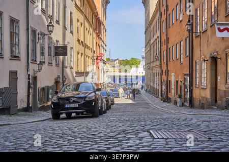 Ein malerischer Blick auf eine Kopfsteinpflasterstraße im historischen Gamla Stan von Stockholm, gesäumt von farbenfrohen traditionellen skandinavischen Gebäuden. In der Stockfoto