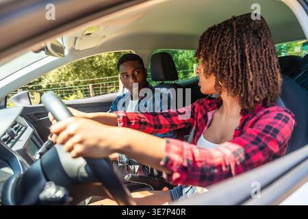Schwarzes und gemischtes Paar, das sich während eines Roadtrips in der Natur an sonnigen Tagen ansieht Stockfoto