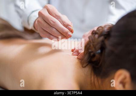 Chinesin, die auf dem Bett lag und Akupunkturbehandlung auf dem Rücken in der Klinik erhielt Stockfoto