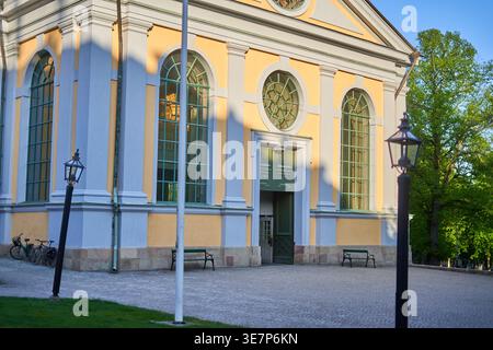 Außenansicht eines historischen neoklassizistischen Gebäudes, wahrscheinlich einer Kirche, mit einer gelb-weißen Fassade und hohen gewölbten Fenstern, die in Grün gerahmt sind. Ein Stockfoto