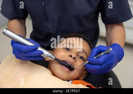 Schwarzer Junge bei Zahnbehandlung mit männlichem Zahnarzt in der Klinik Stockfoto