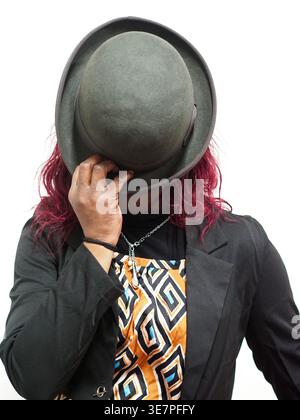 Schwarze Frau mit rotem Haar, das Gesicht mit Hut bedeckt, während sie vor weißem Hintergrund steht Stockfoto