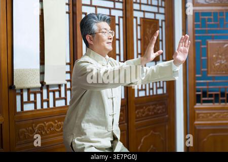 Konzentrierter chinesischer Mann, der zu Hause Tai-Chi praktiziert Stockfoto