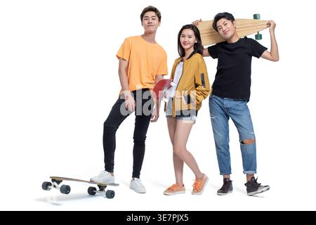 Lächelnde chinesische Freunde stehen mit Skateboards vor weißem Hintergrund im Studio Stockfoto