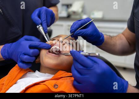 Schwarzer Junge bei Zahnbehandlung mit männlichen Zahnärzten in der Klinik Stockfoto