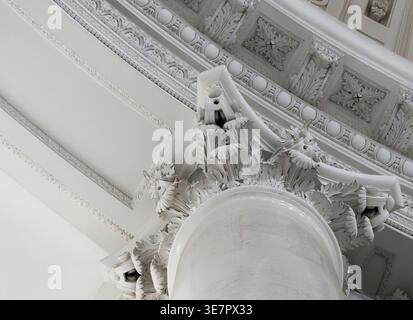 Detaillierte Nahaufnahme einer reich verzierten korinthischen Säulenkapital und dekorativer Stuckdecke Stockfoto