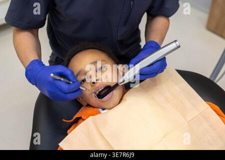 Schwarzer Junge bei Zahnbehandlung mit männlichem Zahnarzt in der Klinik Stockfoto