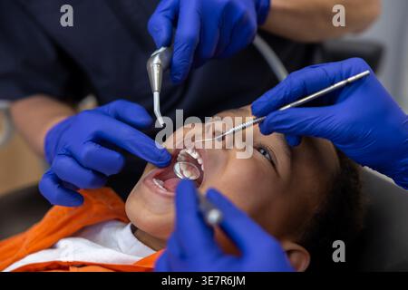 Schwarzer Junge bei Zahnbehandlung mit männlichen Zahnärzten in der Klinik Stockfoto