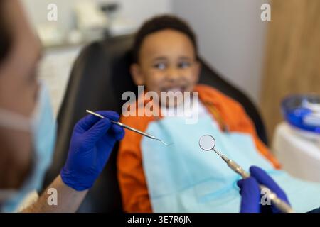 Schwarzer Junge bei Zahnbehandlung mit männlichem Zahnarzt in der Klinik Stockfoto