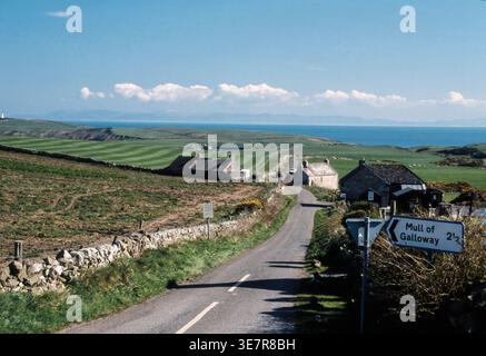 Die malerische Landstraße schlängelt sich in Richtung Mull of Galloway, gesäumt von Steinhäusern und Meerblick. Stockfoto
