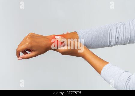 Zugeschnittene Bilder einer schwarzen Frau, die an Arthritis leidet, die ihr Handgelenk vor grauem Hintergrund im Studio reibt Stockfoto