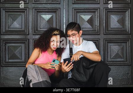 Hispanisches Paar, das tagsüber nahe beieinander vor Holztür sitzt Stockfoto