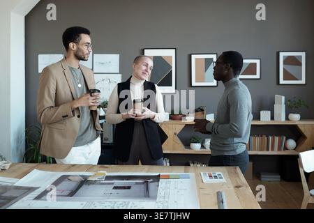 Gruppe von Architekten, die sich mit Kaffee unterhalten, die im Büro stehen Stockfoto