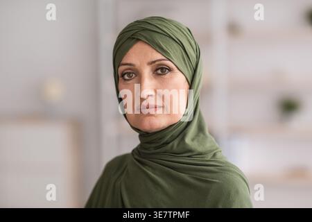 Eine muslimische Frau mittleren Alters im Hijab, die drinnen steht Stockfoto
