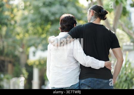 Rückansicht einer älteren Mutter gemischter Rasse, die ihren Sohn umarmt, während sie tagsüber in der Stadt steht Stockfoto