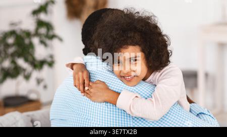 Schwarze Enkelin umarmt Großvater im Wohnzimmer zu Hause Stockfoto