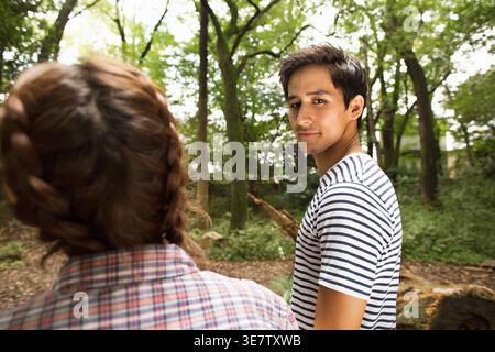 Mann mit gemischter Rasse, der tagsüber neben einer japanischen Freundin im Wald steht Stockfoto