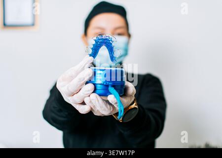 Nicaraguanische Zahnarztgesichtsmaske und Handschuhe mit Halterungen beim Stehen an der weißen Wand in der Klinik Stockfoto