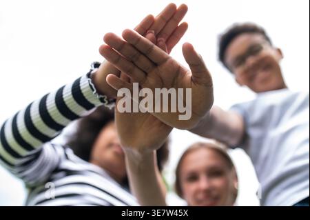 Eine kleine Gruppe von Freunden, die Hände gegen den Himmel stapeln Stockfoto