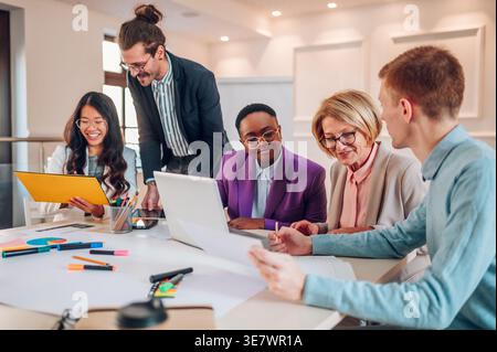 Gruppe von Geschäftsleuten, die sich am Tisch mit Laptop und Dokumenten im Büro treffen Stockfoto