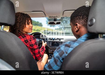 Schwarzes und gemischtes Paar, das sich während eines Roadtrips in der Natur an sonnigen Tagen ansieht Stockfoto