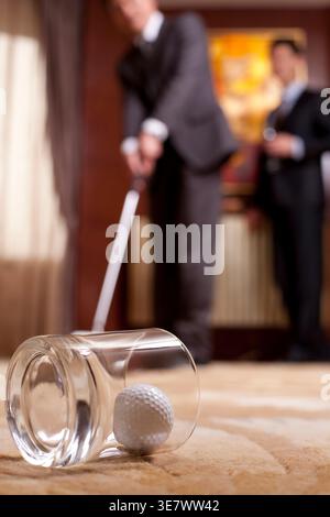 Chinesische Geschäftsleute spielen Golf in einem luxuriösen Zimmer zu Hause Stockfoto