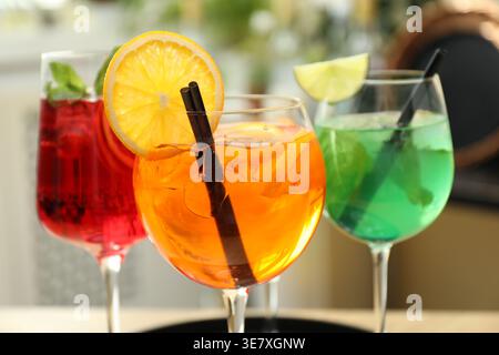 Verschiedene leckere erfrischende Cocktails in Gläsern drinnen, Nahaufnahme Stockfoto