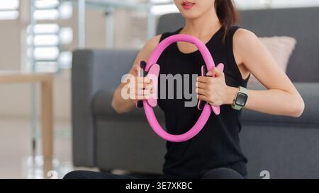 Erwachsene asiatische Frau engagiert sich in effektive Pilates Ring Workout zu Hause verbessern Kern Stärke insgesamt Wellness und Fitness in Innenräumen Stockfoto