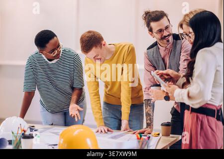 Nahaufnahme einer Gruppe von Architekten, die auf dem Tisch im Büro arbeiten und über Baupläne diskutieren Stockfoto