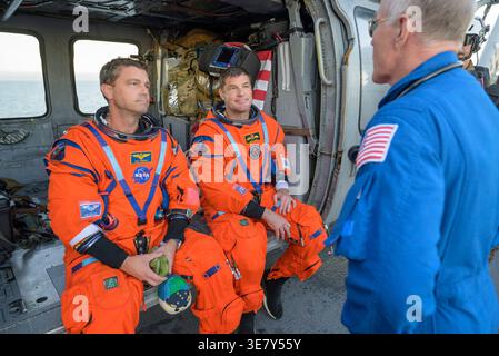 NASA-Astronaut Reid Wiseman, Artemis II-Kommandeur links und CSA (Canadian Space Agency) Astronaut Jeremy Hansen, Artemis II-Missionsspezialist, sprechen mit dem NASA-Flugchirurgen Richard Scheuring bei ihrer Navy MH-60 Seahawk von der Helicopter Sea Combat Squadron (HSC) 23 auf dem Flugdeck der USS John P. Murtha, nachdem sie und andere Besatzungskameraden der NASA-Astronauten Victor Glover, und Christina Koch wurde nach dem Spritzen am Freitag, 10. April 2026, im Pazifik vor der Küste Kaliforniens aus ihrem Orion-Raumschiff extrahiert. Die Artemis-II-Mission der NASA nahm das Quartett mit auf eine fast zehntägige Reise Stockfoto