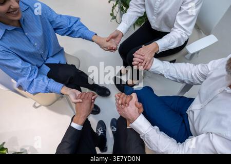 Schwarzer Mann mit kaukasischen Kollegen, die während der Psychotherapiesitzung im Kreis auf Stühlen sitzen Stockfoto